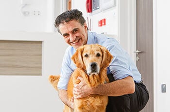 Supervet Noel Fitzpatrick is kneeling on the ground, interacting lovingly with a golden retriever