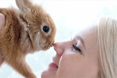 A ginger rabbit nose to nose with a women.