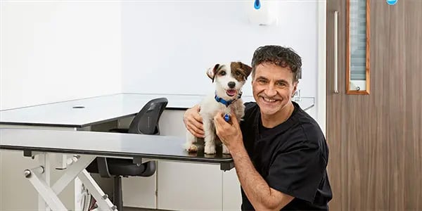 Veterinarian Noel Fitzpatrick smiling and holding a Jack Russell Terrier.