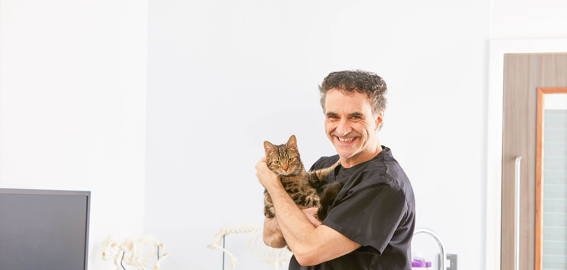 Veterinarian Noel Fitzpatrick cuddling a brown cat.